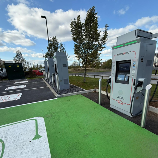 Close-up of InstaVolt ultra-rapid electric vehicle chargers in a landscaped car park, featuring dedicated EV bays with green markings and clear signage.