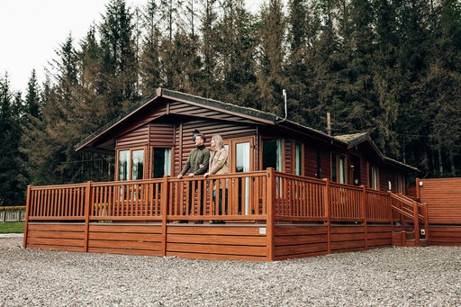 Couple stand outside one of our lodges and admire the view of Loch Awe Holiday Park