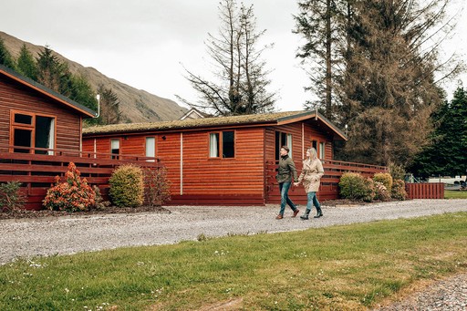 Couple stroll past some of our lodges at Loch Awe Holiday Park