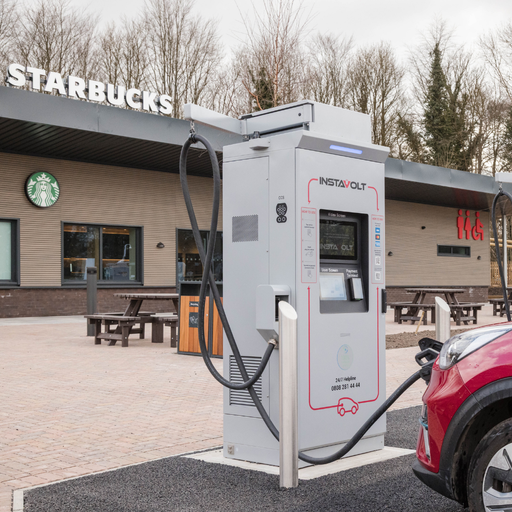 An InstaVolt ultra rapid charging unit positioned outside a Starbucks, with a red EV plugged in.