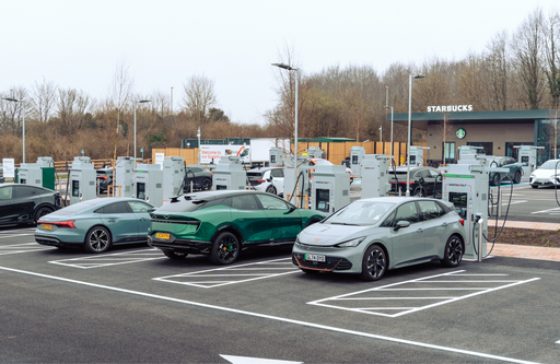 A busy InstaVolt superhub showing multiple EVs charging simultaneously, with clear signage, ultra rapid chargers, and a Starbucks café in view.