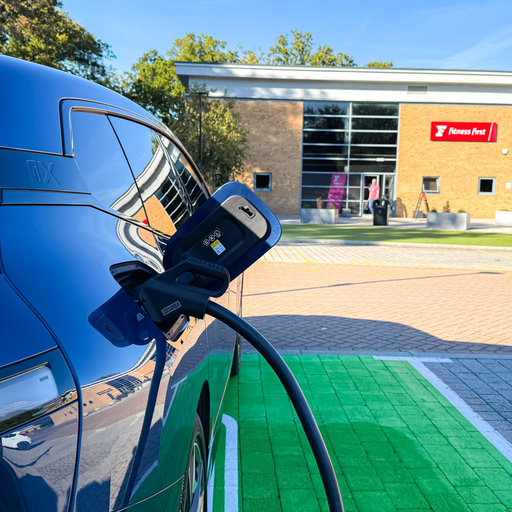 A BMW charges at an InstaVolt unit, parked in a green bay with smart landscaping.