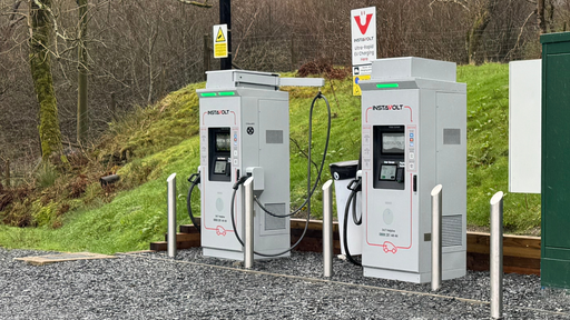 Front view of InstaVolt ultra-rapid charging units at Plas Weunydd, featuring contactless payment terminals and protective bollards in a scenic woodland setting.