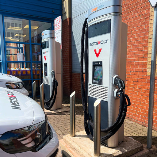 Two InstaVolt EV chargers outside Halfords in Sheldon, Birmingham, with vehicles parked in front. The chargers are easily accessible beside the store entrance, making it ideal for quick charging during shopping trips.