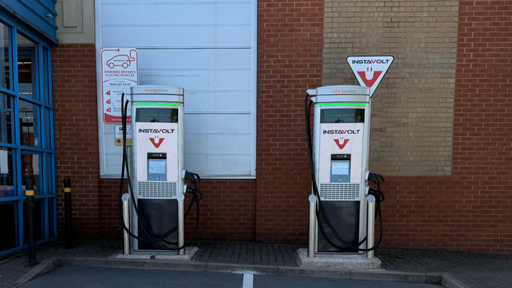 A front-on view of the InstaVolt charging station at Halfords in Sheldon, Birmingham, showing two charging units and clearly marked EV bays. Positioned for easy access within Wells Lane Retail Park.