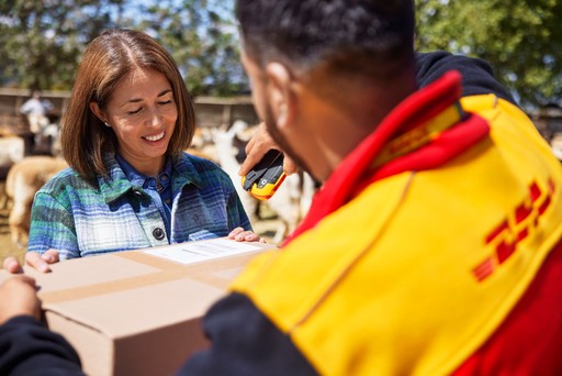 DHL Express courier scanning a parcel during delivery to a customer outdoors.