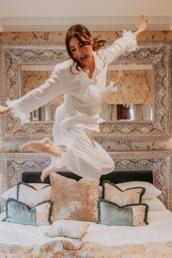 Bride jumping on bed at Eaves Hall, Clitheroe