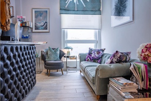 Welcoming reception and waiting area at The Harrogate Clinic featuring a tufted reception desk, plush velvet sofa, contemporary artwork, and fresh flowers, creating a relaxing first impression for dental and aesthetic patients in Harrogate.