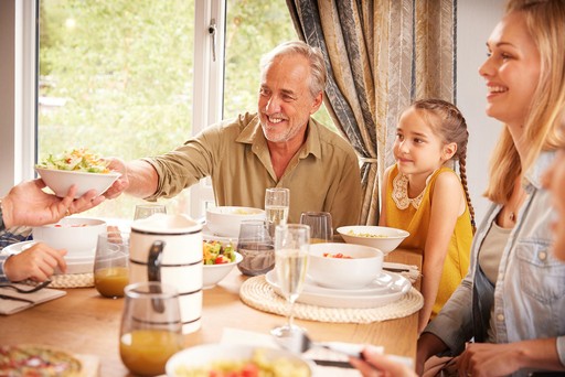 Family enjoy a dinner around the table in their lodge at Loch Lomond
