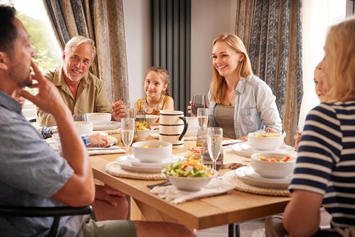 Family enjoy a meal around the table in their lodge at Loch Lomond