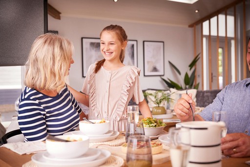 Family enjoy a meal around the table in their lodge at Loch Lomond