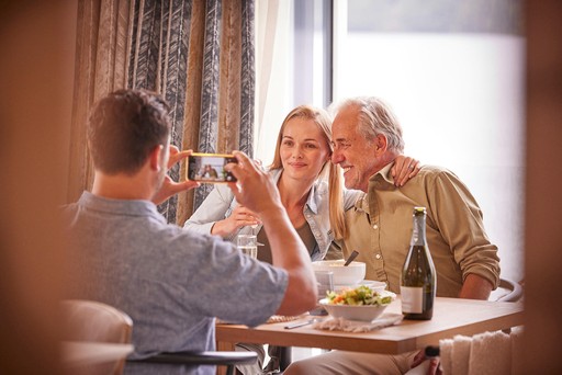 Family enjoy a meal around the table in their lodge at Loch Lomond
