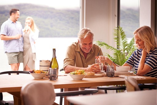 Couple enjoy drinks at the table in their lodge at Loch Lomond