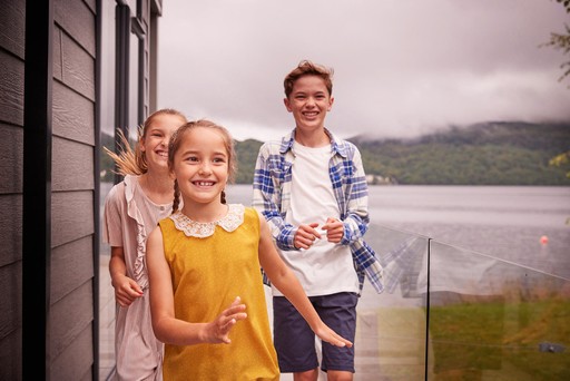 Kids run along the decking on their lodge at Loch Lomond