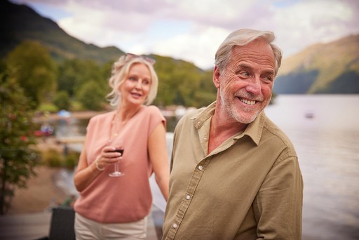 Couple relax on the veranda of their lodge at Loch Lomond Holiday Park
