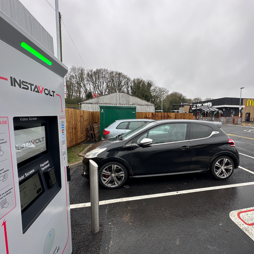 An InstaVolt electric vehicle charger located in a McDonald’s car park, with a vehicle parked nearby and clear access to the charging space.