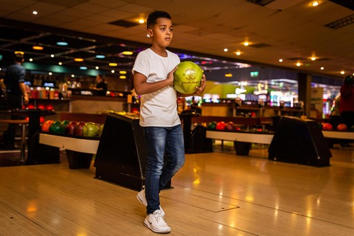 Young boy approaching the bowling lane with his bowling ball in hand ready to bowl