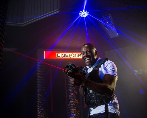 Young male adult playing a game of laser tag using the laser gun and wearing protective gear with strobe lighting